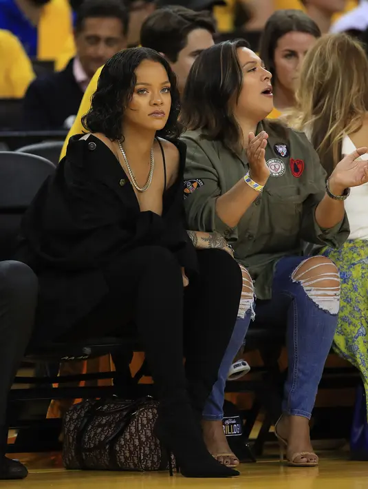 Ekspresi Rihanna menyaksikan pertandingan gim pertama Final NBA 2017 antara Golden State Warriors melawan Cleveland Cavaliers di Oracle Arena, Oakland, (1/6). Rihanna tampil dengan busana berwara hitam. (Ezra Shaw/Getty Images/AFP)