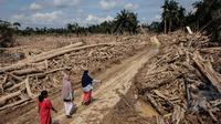 Aceh Tamiang menjadi salah satu daerah yang paling terdampak bencana banjir bandang Sumatera yang terjadi pada (26/11/2025) lalu. Tampak dalam foto, para wanita melintasi jalan yang telah dibersihkan dari pohon-pohon tumbang pasca banjir bandang di Aceh Tamiang, pada Rabu 10 Desember 2025. (Aditya Aji/AFP)