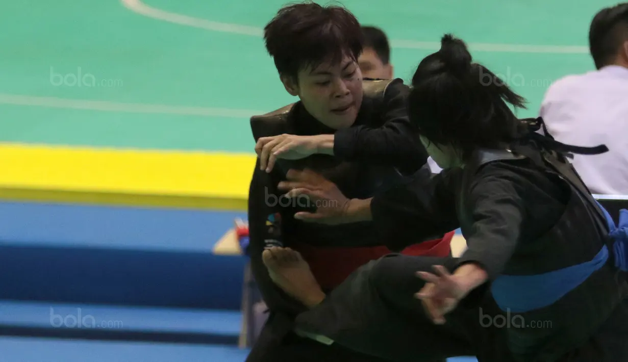 Pesilat Indonesia, Octaviani Nirmalasari (kiri) menahan tendangan pesilat Laos, Olahthai Sounthavong pada semifinal Test Event Pencak Silat 2018 di Padepokan Silat TMII, Jakarta, (12/2/2018). Oktaviani menang 5-0. (Bola.com/Nick Hanoatubun)