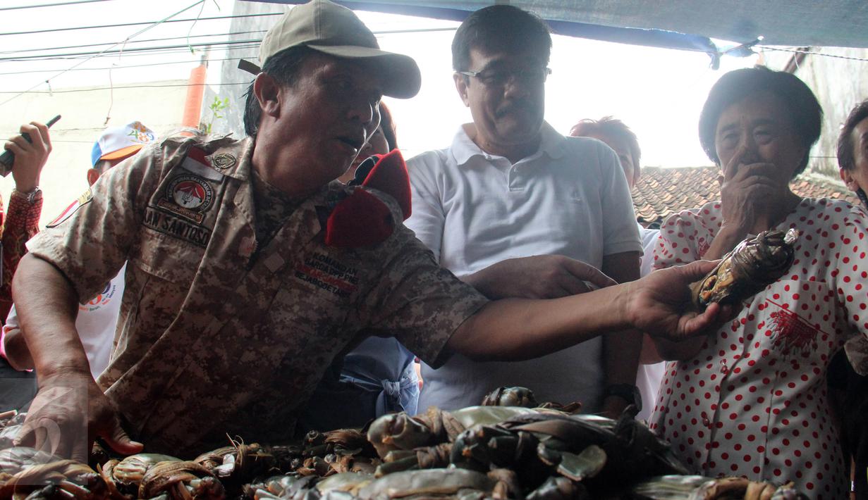 Wagub DKI Jakarta, Djarot Saiful Hidayat (baju putih) memilih kepiting saat blusukan ke Pasar Petak Sembilan, Jakarta, Sabtu (18/6). Selain berbincang-bincang Djarot juga memborong sejumlah sayuran yang dijual para pedagang. (Liputan6.com/Helmi Afandi)