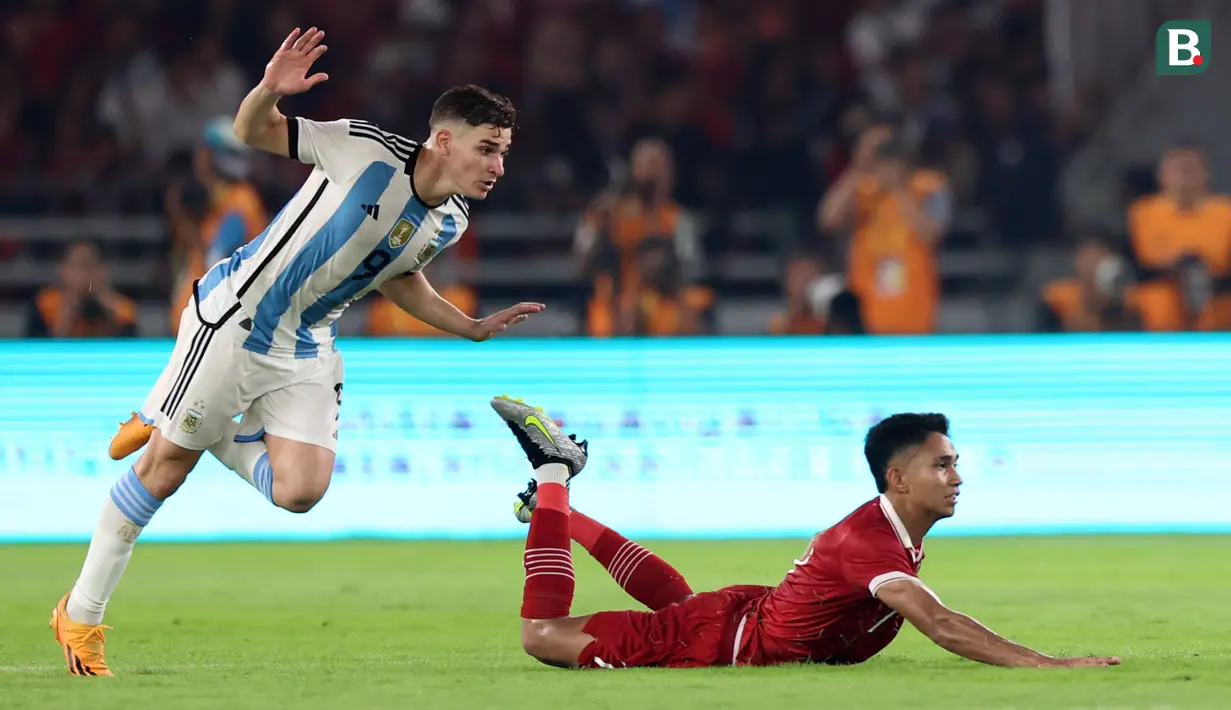 Pemain Timnas Indonesia, Marselino Ferdinan (kanan) terjatuh ketika berebut dengan pemain Argentina, Julian Alvarez pada laga FIFA Matchday di Stadion Utama Gelora Bung Karno (SUGBK), Senayan, Jakarta, Senin (19/06/2023). (Bola.com/Bagaskara Lazuardi)