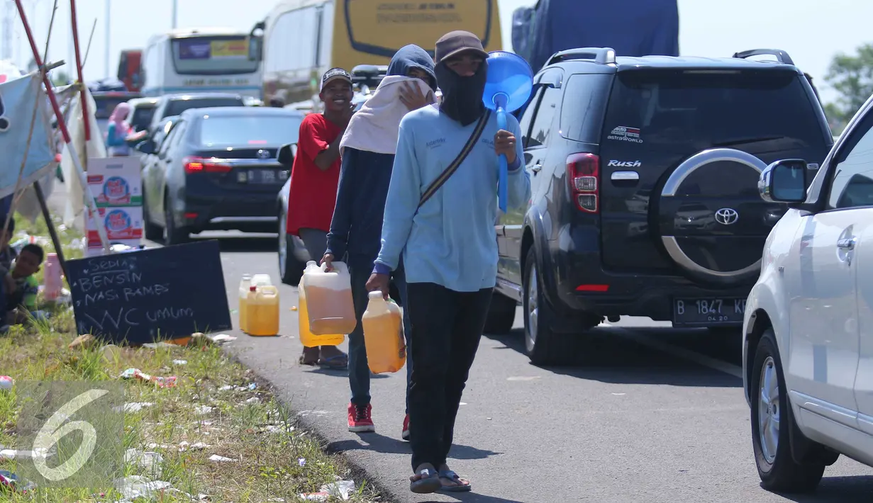 Warga menjual bensin kepada para pemudik yang mengantri di pintu tol Brebes Timur, Minggu (3/7). Antrian panjang di pintu keluar tersebut di manfaatkan warga sekitar untuk berjualan bensin eceran. (Liputan6.com/Angga Yuniar)
