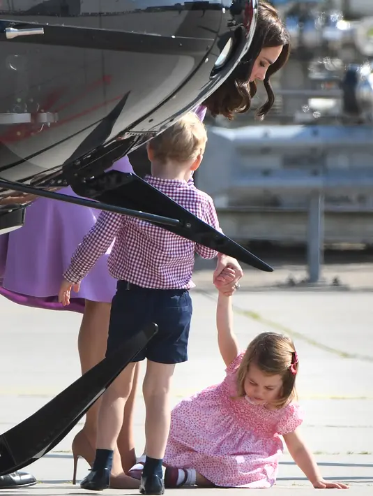 Kate Middleton membujuk anak keduanya, Putri Charlotte, saat hendak naik helikopter dalam kunjungannya ke Pabrik Airbus, di Hamburg, Jerman, 21 Juli 2017. Putri Charlotte menangis hingga terduduk di lantai dekat helikopter. (Patrik STOLLARZ / AFP)