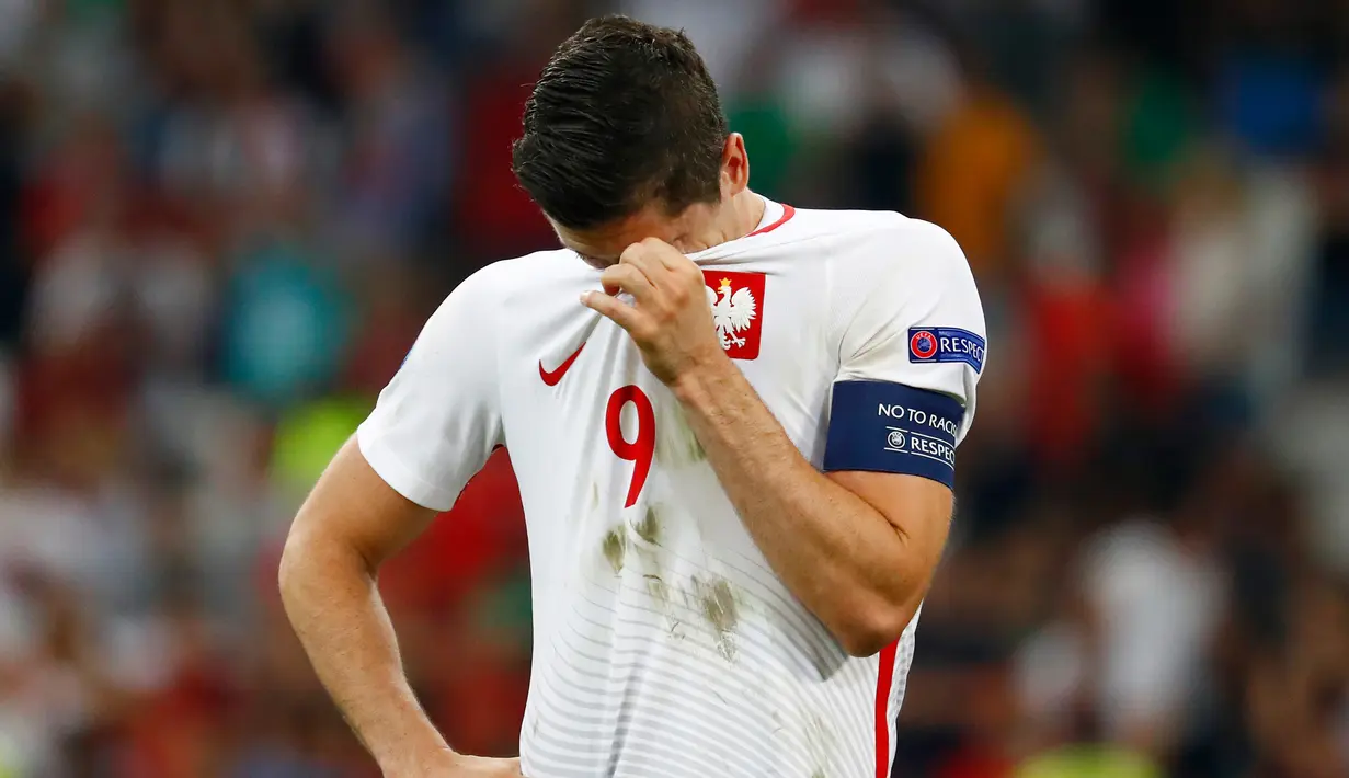Penyerang Polandia, Robert Lewandoski menutup wajahnya usai pertandingan melawan Portugal pada perempat final Piala Eropa di Stade Velodrome, Perancis, (1/7). Portugal melaju ke Semifinal usai menang adu penalti dengan skor 5-3. (REUTERS /Michael Dalder)