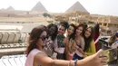 Para Kontestan Miss ECO Universe berselfie menggunakan tongsis dengan latar belakang segitiga piramida di pinggiran Kairo, Mesir (10/4). Pemenang Miss Eco Universe 2016 akan memenangkan hadiah uang tunai USD 10.000. (REUTERS/Mohamed Abd El Ghany)