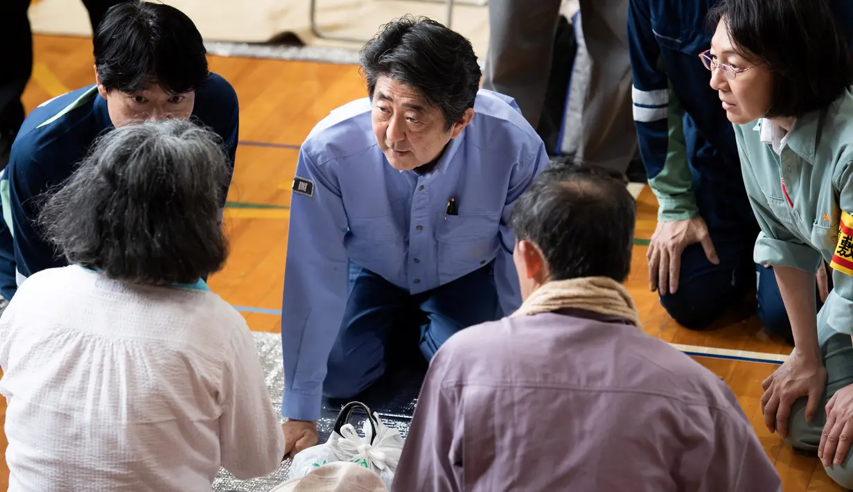 Perdana Menteri Jepang Shinzo Abe mengunjungi lokasi penampungan korban banjir di Mabi, Prefektur Okayama, Rabu (11/7). Sebelumnya, Abe sudah membatalkan rencana perjalanan luar negeri karena bencana yang kian memburuk. (AFP/Martin BUREAU)
