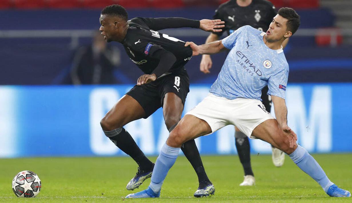 Pemain Manchester City, Rodrigo, berebut bola dengan pemain Borussia Moenchengladbach, Denis Zakaria, pada laga Liga Champions di Puskas Arena, Kamis (25/02/2021). City menang dengan skor 2-0. (AP/Laszlo Balogh)