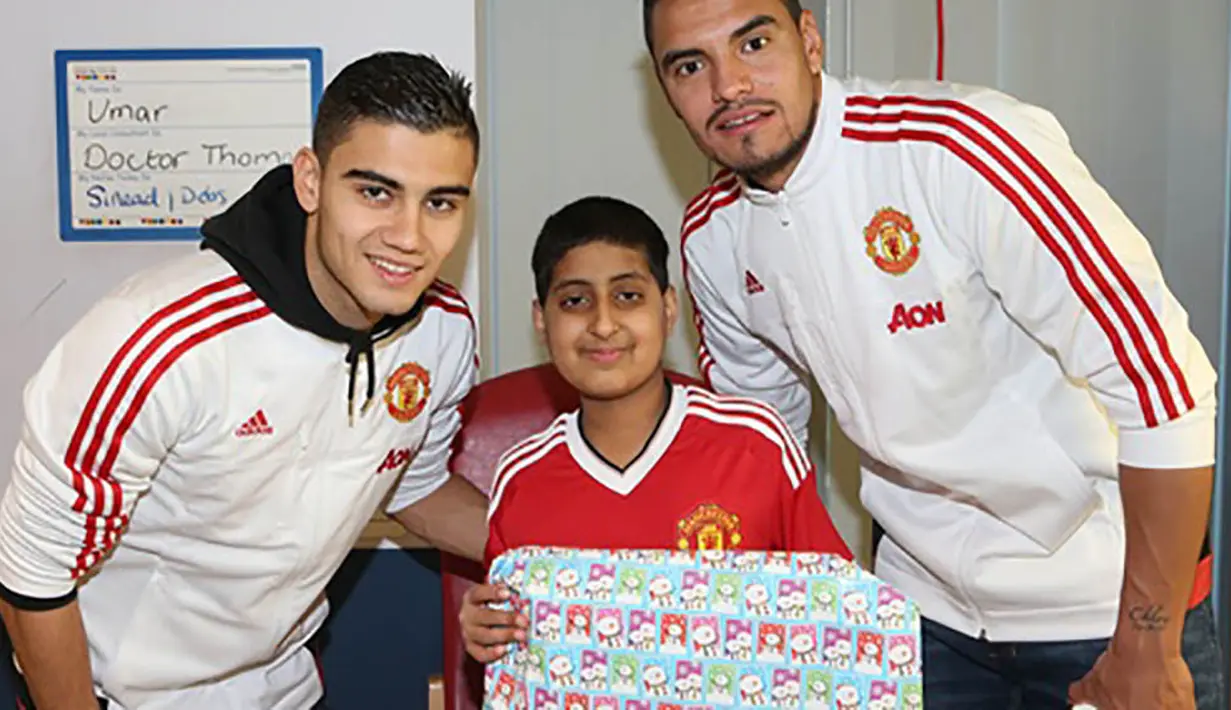 Kiper MU, Sergio Romero dan rekan setimnya, Andreas Perreira memberikan kado kepada pasien dari Rumah Sakit Royal Manchester Children. (www.manutd.com)
