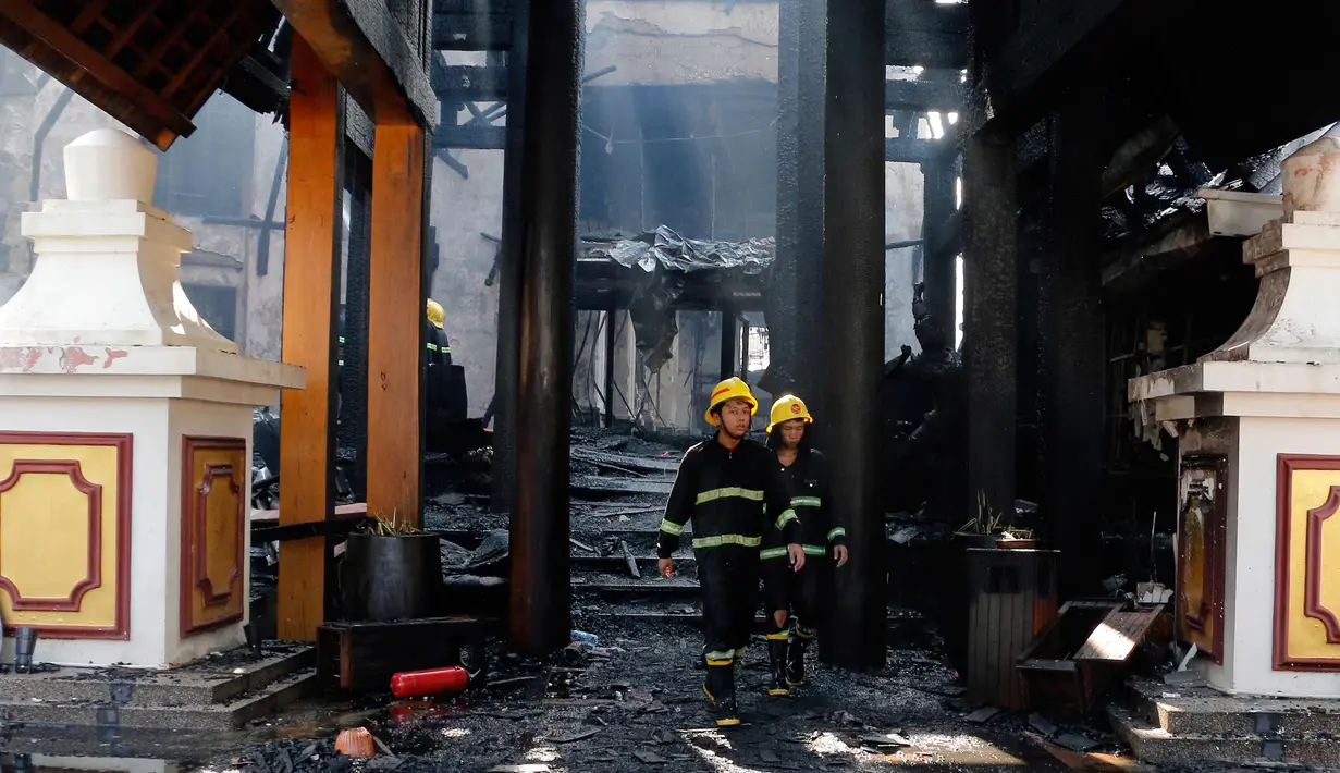 Petugas berjalan di sebuah bangunan yang terbakar di Hotel Istana Kandawgyi di Yangon, Myanmar (19/10). Api telah melahap hotel bintang lima yang sering dikunjungi wisatawan asing di kota Yangon, Myanmar. (AP Photo/Thein Zaw)
