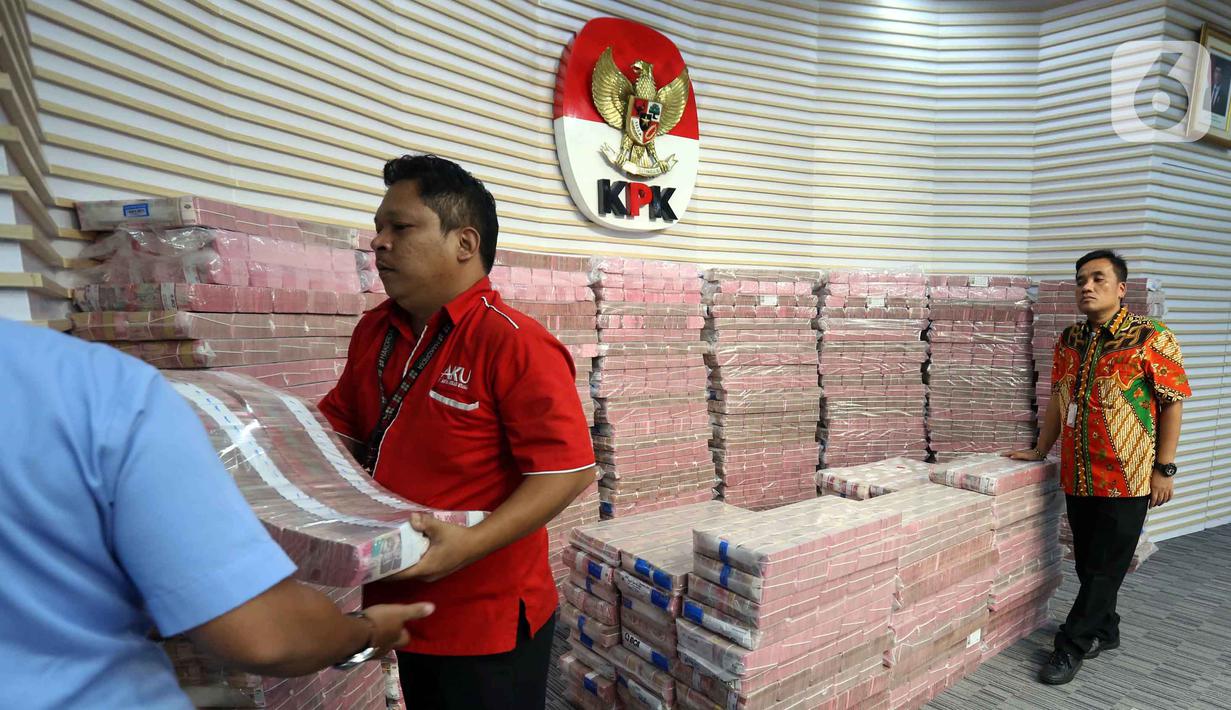 Petugas mengangkut uang dari tumpukan sebesar Rp 300 miliar yang dipamerkan di gedung Merah Putih Komisi Pemberantasan Korupsi (KPK), Jakarta, Kamis (20/11/2025). Komisi Pemberantasan Korupsi (KPK) memamerkan uang tunai sebesar Rp 300 miliar. (Liputan6.com/Helmi Fithriansyah)