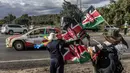 Pembalap Italia, Riccardo Garosci memacu mobilnya, Mitsubishi Lancer Evo X bersama co-driver Rudy Briani melewati pedagang bendera Kenya dan vuvuzelas saat Safari Relly Kenya di Naivasha, Kenya, 28 Maret 2024. (AFP/Luis Tato)