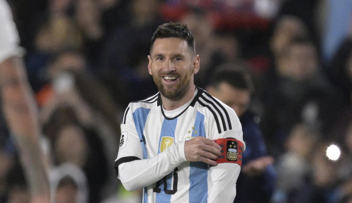 Pemain Timnas Argentina, Lionel Messi, yang baru bermain dari bangku cadangan hanya bisa tersenyum ketika rekan satu timnya Nicolas Otamendi memberikan ban kapten saat pertandingan Kualifikasi Piala Dunia 2026 zona CONMEBOL melawan Paraguay di Stadion Mas Monumental, Jumat (13/10/2023) pagi WIB. (AFP/Juan Mabromata)
