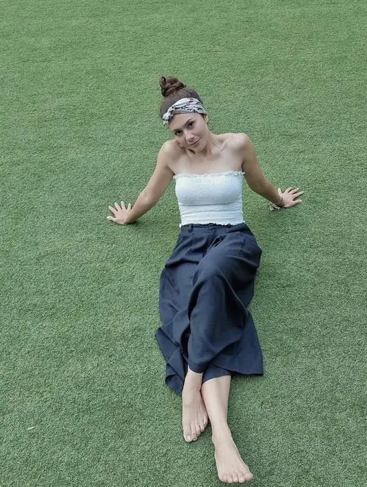 <p>Tampil feminin, Wulan terlihat memadukan bandeau top warna putih, rample skirt warna hitam, dan bandana warna putih senada. (Instagram/wulanguritno).</p>
