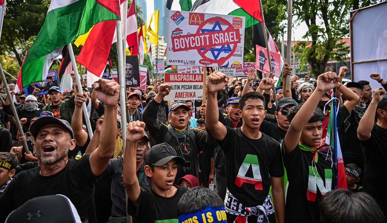 Sebagai informasi, Hari Al-Quds Internasional diperingati setiap Jumat terakhir bulan Ramadan. Tampak dalam foto, orang-orang memegang plakat dan bendera Palestina selama berunjuk rasa memperingati Hari Al-Quds, di Surabaya, Jawa Timur, Jumat (13/3/2026). (Juni KRISWANTO/AFP)