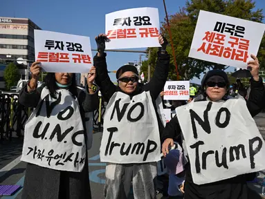 Para demonstran Korea Selatan yang mengenakan spanduk bertuliskan "Tolak Trump" memegang plakat selama demonstrasi yang mengecam tekanan Presiden AS Donald Trump untuk meningkatkan investasi Korea Selatan di AS, di Gyeongju pada 29 Oktober 2025, menjelang KTT Kerja Sama Ekonomi Asia-Pasifik (APEC). (Jung Yeon-je/AFP)
