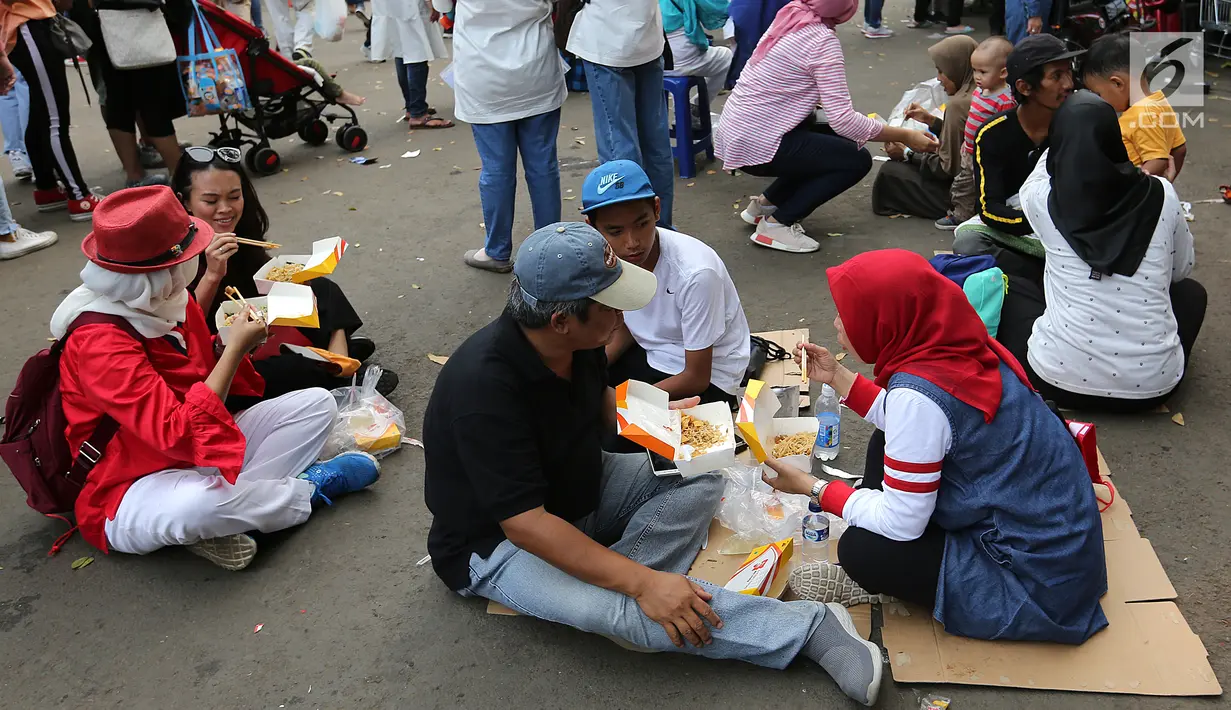 Pengunjung menikmati makan sambil lesehan jelang Closing Ceremony Asian Games 2018 di kawasan Gelora Bung Karno, Jakarta, Minggu (2/9). Mereka tidak mendapatkan kursi makan karena dipadati pengunjung. (Liputan6.com/Fery Pradolo)