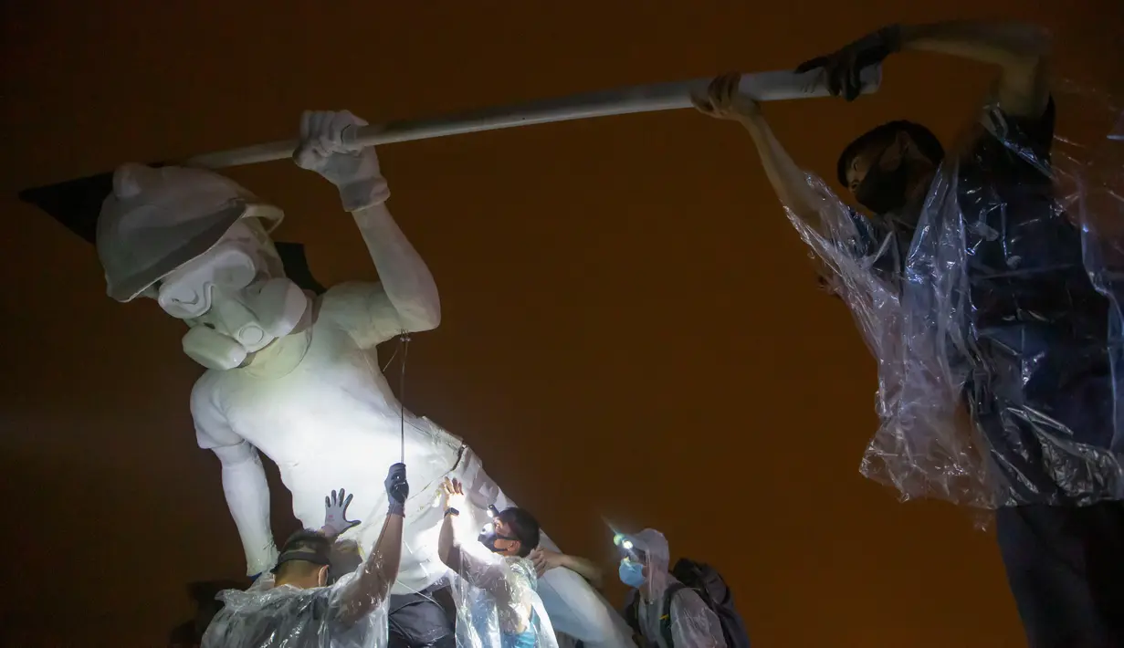 Demonstran antipemerintah mendirikan patung The Lady Liberty of Hong Kong di puncak pegunungan Lion Rock, Hong Kong, Minggu (13/10/2019). Demonstran mengerek patung tersebut meski badai petir melanda semalaman. (AP Photo/Kin Cheung)