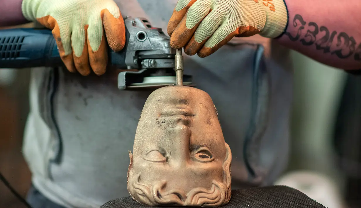 Fettler Piotr Lichon menghaluskan topeng BAFTA (British Academy of Film and Television Awards) saat proses pembuatan di New Pro Foundries, London, 21 Januari 2020. Topeng piala ini akan dibagikan dalam malam anugerah BAFTA Awards pada 2 Februari mendatang. (JUSTIN TALLIS / AFP)