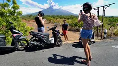 Sejumlah turis mengabadikan pemandangan erupsi Gunung Agung di Kabupaten Karangasem, Bali, Jumat (6/7). Erupsi Gunung Agung mengundang banyak perhatian warga dan wisatawan. (AFP FOTO / Sonny Tumbelaka)