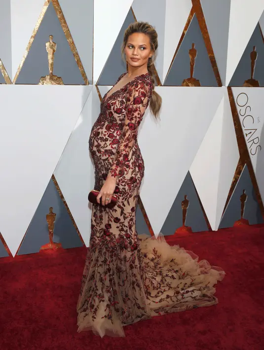Istri dari John Legend, Chrissy Teigen tampil memesona pada red carpet Oscar 2016 dalam gaun merah ketat yang memamerkan belahan dada dengan aksen bunga-bunga, di Hollywood & Highland Center, Hollywood, California, Minggu (28/2). (REUTERS/Lucy Nicholson)