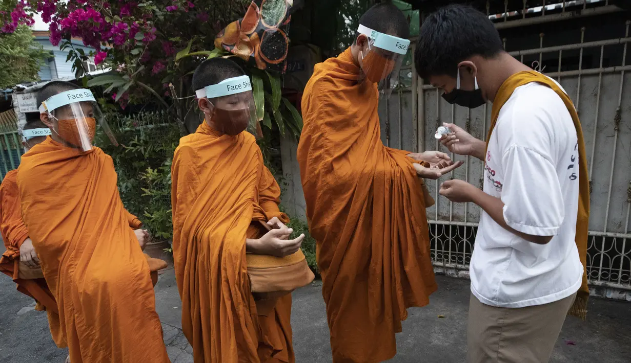 Warga memberikan gel alkohol kepada para biksu Buddha yang memakai pelindung wajah untuk melindungi diri dari virus corona COVID-19 saat mengumpulkan sedekah di Bangkok, Thailand, Selasa (31/3/2020). Hingga 30 Maret 2020 sore, kasus positif COVID-19 di Thailand ada 1.524. (AP Photo/Sakchai Lalit)