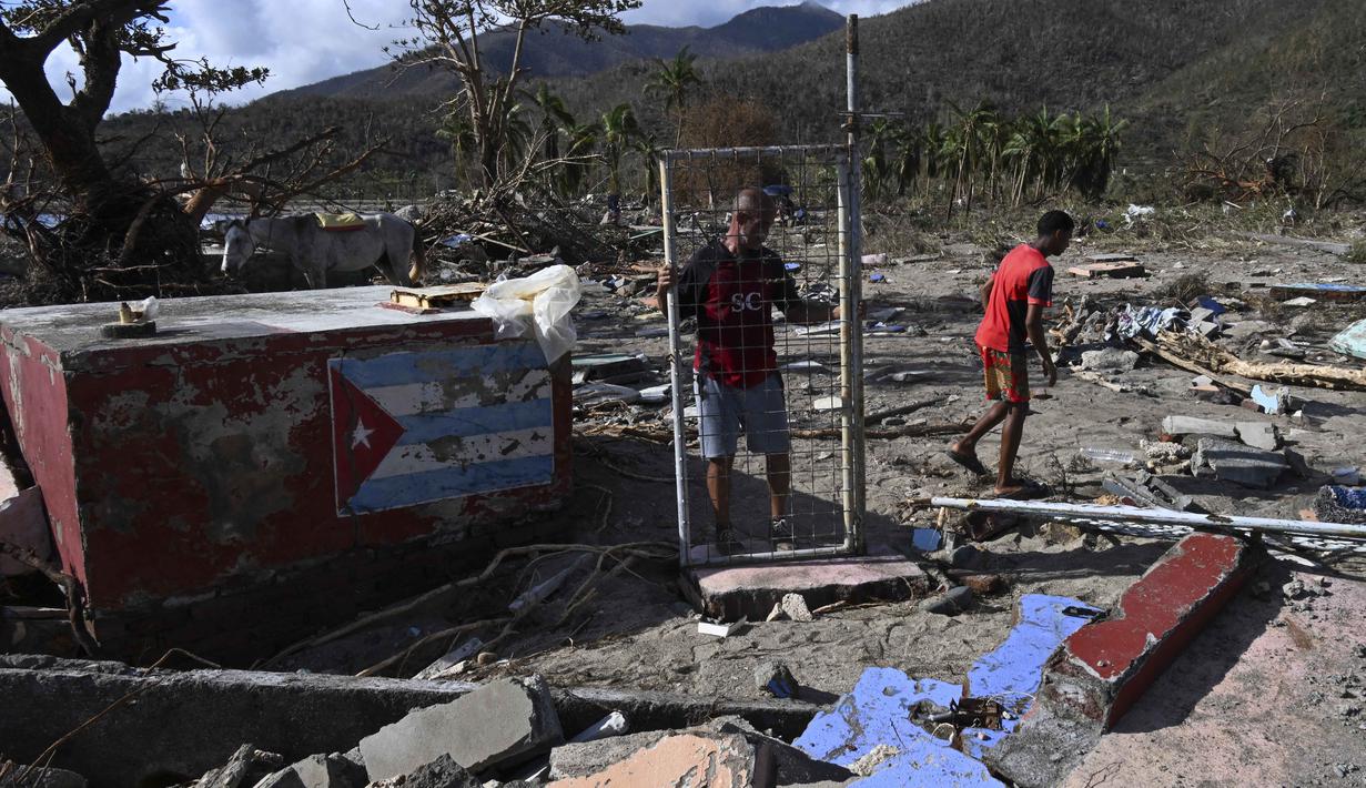 Seorang pria memegang gerbang rumah yang rusak akibat Badai Melissa di desa Boca de Dos Rios, provinsi Santiago de Cuba, Kuba, pada Kamis 30 Oktober 2025. Pada Rabu (29/10/2025), pagi waktu setempat, sejumlah pejabat melaporkan beberapa rumah runtuh, jalan pegunungan terblokir, dan atap bangunan beterbangan akibat terjangan Badai Melissa. 
(YAMIL LAGE/AFP)