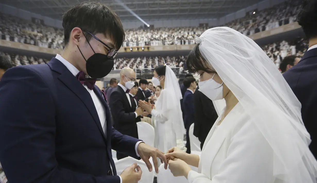 Pengantin wanita mamasangkan cincin ke jari pasangannya selama mengikuti pernikahan massal di Cheong Shim Peace World Center, Gapyeong, Korea Selatan, Jumat, (7/2/2020). Kegiatan pernikahan massal ini digelar setiap tahun dan diikuti juga oleh pasangan asing. (AP Photo/Ahn Young-joon)