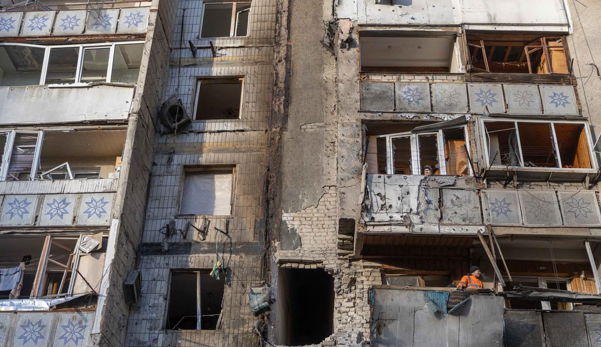 Otoritas setempat pada Rabu 31 Desember 2025 mengatakan, serangan tersebut merusak bangunan tempat tinggal dan infrastruktur. Tampak dalam foto, warga berdiri di balkon sebuah bangunan tempat tinggal yang rusak akibat serangan di Odesa, pada 31 Desember 2025, di tengah invasi Rusia di Ukraina. (Oleksandr GIMANOV/AFP)