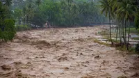 Data Pusat Pengendalian Operasi Penanggulangan Bencana (Pusdalops) BPBD Padang, Kecamatan Koto Tangah menjadi wilayah dengan jumlah terdampak terbesar, yaitu 20.983 warga. Tampak dalam foto, warga bertahan di tepi sungai saat banjir melanda Padang, Provinsi Sumatra Barat, pada Kamis 27 November 2025. (REZAN SOLEH/AFP)