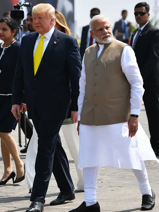 PM India, Narendra Modi berjalan dengan Presiden AS Donald Trump dan Melania Trump saat menyambut mereka di Bandara Internasional Sardar Vallabhbhai Patel di Ahmedabad, Senin (24/2/2020). Kunjungan Trump selama dua hari ini dipersiapkan secara matang berminggu-minggu sebelumnya. (MANDEL NGAN/AFP)