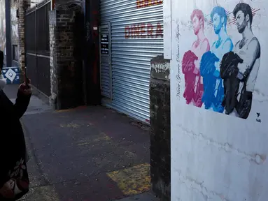 Seorang wanita mengambil gambar mural musisi asal Inggris, George Michael, di Shoreditch, London timur, 29 Desember 2016. Mural itu diciptakan seorang seniman jalanan Pegasus sebagai penghormatan terhadap mendiang George Michael. (REUTERS/Stefan Wermuth)