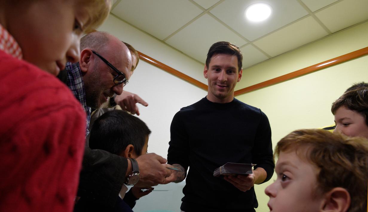 Bintang Barcelona, Lionel Messi melayani permintaan tanda tangan para pasien anak-anak saat melakukan kunjungan amal di Rumah Sakit Barcelona, Senin (4/1/2016). (AFP PHOTO / Lluis GENE)