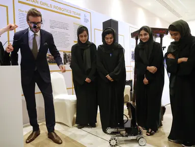 Mantan pemain sepak bola Inggris dan duta UNICEF, David Beckham bermain dengan robot yang dibuat oleh Tim Robotika Putri Afghanistan di Forum Doha di ibukota Qatar (27/3/2022). (Marwan Tahtah/Mofa/Doha Forum)