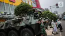 Dua siswa berjalan dekat  Prajurit TNI dan  satu unit kendaraan Anoa di kawasan LTC Glodok, Jakarta, Jumat (18/10/2019). Penjagaan tersebut guna memberikan rasa aman bagi masyarakat menjelang pelantikan presiden dan wakil presiden terpilih, 20 Oktober 2019. (Liputan6.com/Faizal Fanani)