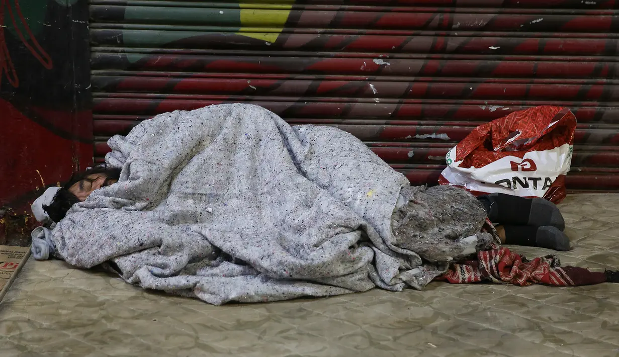 Seorang tunawisma tidur di atas trotoar saat malam dengan cuaca dingin di pusat kota Sao Paulo, 19 Juli 2017. Menurut pejabat setempat, setidaknya 16.000 tunawisma tinggal di kota Sao Paulo. (AP Photo / Andre Penner)
