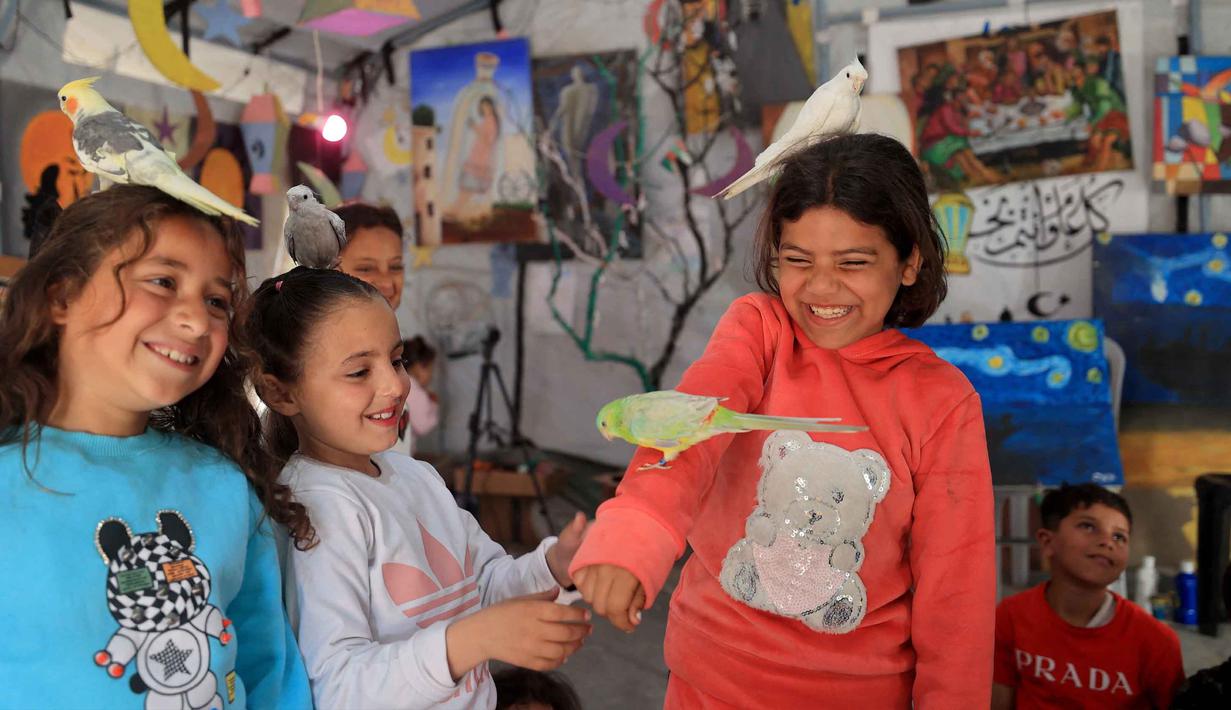 Sebelumnya, pada Maret 2026, Badan Perserikatan Bangsa Bangsa (PBB) untuk kesehatan seksual dan reproduksi, United Nations Population Fund (UNFPA) mengatakan lebih dari satu juta anak di Gaza yang membutuhkan layanan kesehatan mental dan dukungan psikososial. Tampak dalam foto, anak-anak pengungsi Palestina mengikuti sesi konseling psikologis di sebuah studio seni yang menggunakan hewan peliharaan dan burung di daerah Al-Zawaida, Jalur Gaza Tengah, pada Selasa 21 April 2026. (Eyad Baba/AFP)