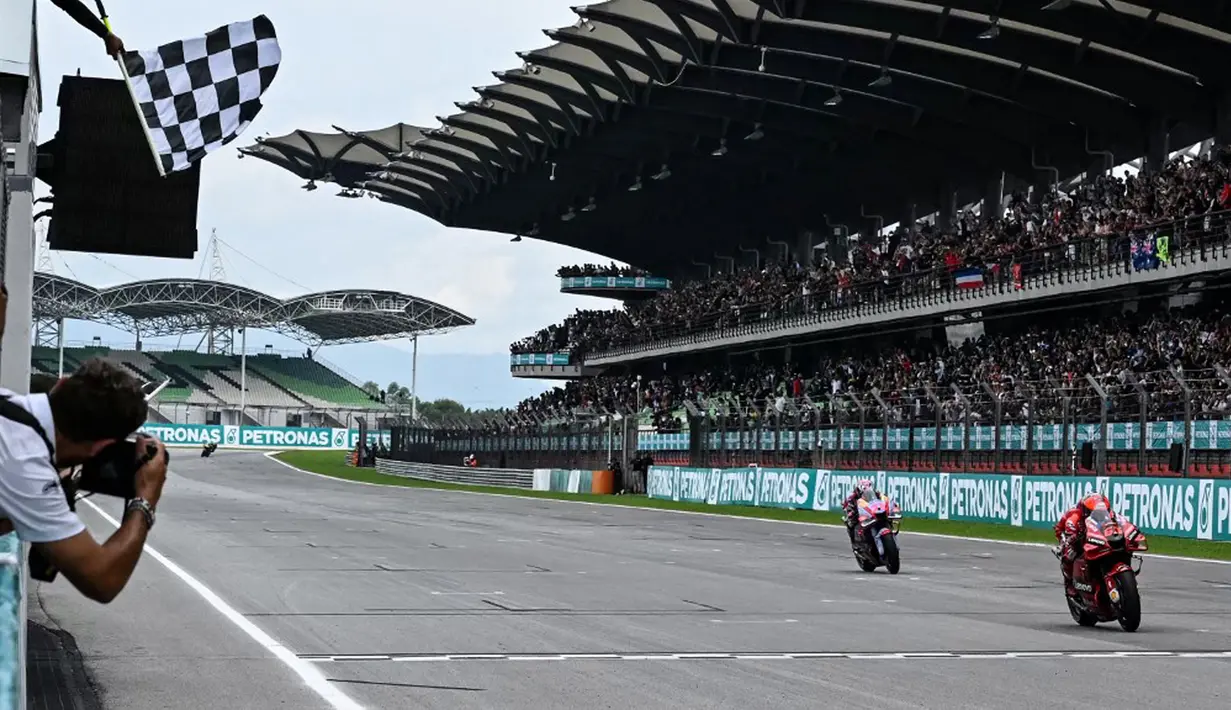Pembalap Ducati Lenovo Francesco Bagnaia melintasi garis finish untuk menang di depan pembalap Ducati Gresini Racing Enea Bastianini saat balapan MotoGP Malaysia 2022 di Sirkuit Internasional Sepang, Sepang, Malaysia, Minggu (23/10/2022). Francesco Bagnaia sukses menjadi juara MotoGP Malaysia 2022 disusul Enea Bastianini dan Fabio Quartararo. (MOHD RASFAN/AFP)