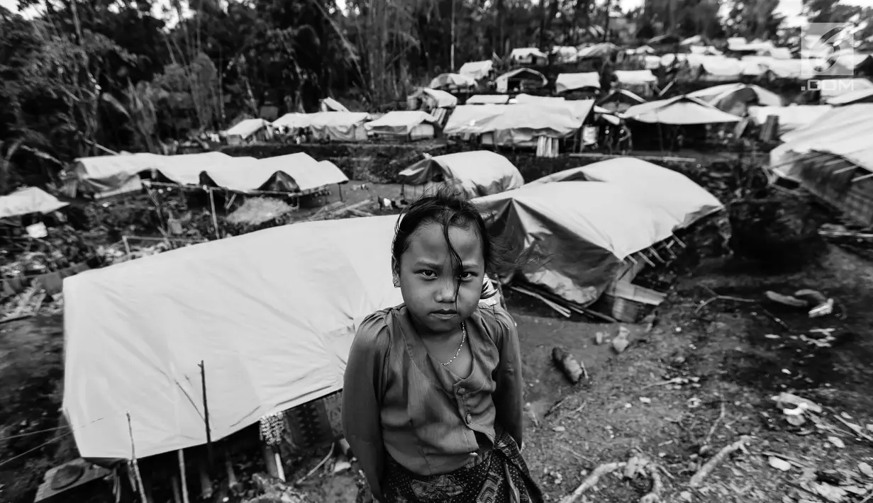 Seorang anak perempuan pose dengan latar belakang puluhan rumah Suku Baduy Luar setelah terbakar di Kampung Cisaban II, Desa Kanekes, Banten, Kamis (1/6). Kebakaran pada pekan lalu yang menghanguskan 83 rumah Suku Baduy Luar. (Liputan6.com/Fery Pradolo)