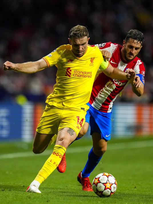 Pemain Liverpool Jordan Henderson (kiri) berduel memperebutkan bola dengan pemain Atletico Madrid Koke pada pertandingan sepak bola Grup B Liga Champions di Stadion Wanda Metropolitano, Madrid, Spanyol, Selasa (19/10/2021). Liverpool menang 3-2. (AP Photo/Manu Fernandez)