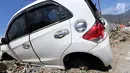 Sebuah mobil Honda Brio menjadi incaran jarahan korban gempa dan tsunami di Palu Grand Mal, Palu, Jumat (5/10). Warga korban gempa bumi mengambil ban dan interior mobil. (Liputan6.com/Fery Pradolo)