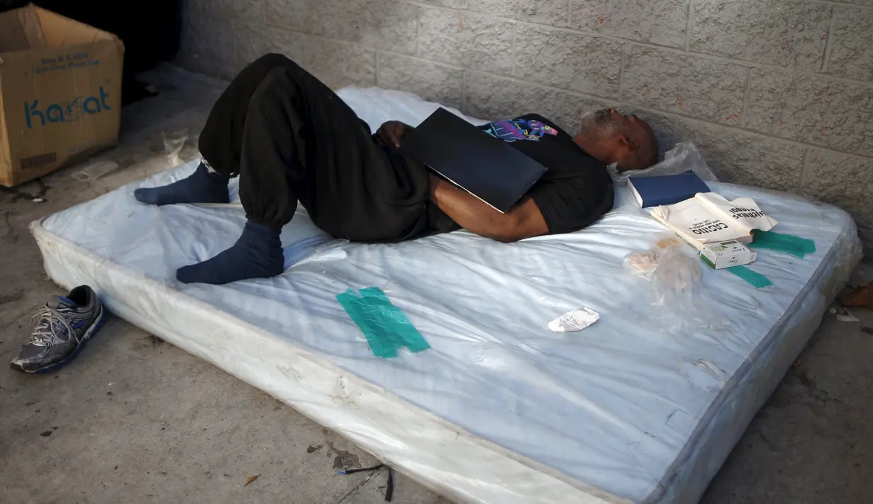 Seorang pria tertidur di atas matras di kawasan kid Row, Los Angeles, California, Kamis (1/10/2015). Kota Los Angeles menetapkan status darurat terkait makin rumitnya persoalan kaum tunawisma di sana. (REUTERS/Lucy Nicholson)