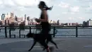 Seorang wanita bersama anjingnya berlari selama musim semi yang hangat di tepi air di Manhattan di New York City (8/4). Sebagian besar Pantai Timur mengharapkan suhu hangat terus sepanjang minggu. (Spencer Platt/Getty Images/AFP)