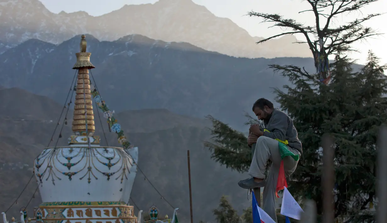 Seorang pria berada di atas tiang untuk memasang bendera warna-warni pada hari ketiga Tahun Baru Tibet di Dharmsala, India (18/2). Umat Buddha Tibet percaya, bendera warna-warni berisi doa itu akan menyebarkan doa ke dunia. (AP/Ashwini Bhatia)