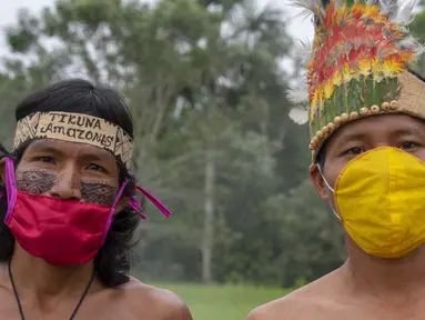 Suku Tikuna berpose mengenakan masker di tengah kekhawatiran virus corona Covid-19 di Leticia, Departemen Amazonas, Kolombia pada 8 Juni 2020. Kasus virus corona ini meningkatkan kekhawatiran akan resiko penyebaran ke masyarakat adat yang rentan dan berada di pedalaman. (Tatiana de NEVO/AFP)