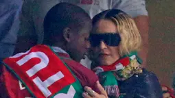 Penyanyi AS, Madonna berbincang dengan anaknya David Banda menyaksikan pertandingan kualifikasi Piala Dunia 2018 antara Portugal dan Swiss di Stadion Luz di Lisbon (10/10). Portugal menang 2-0 atas Swiss. (AFP Photo/Francisco Leong)