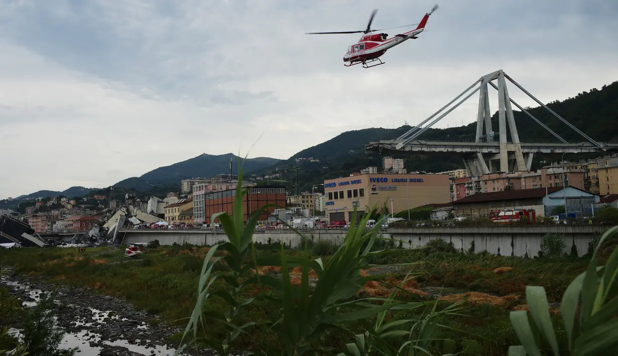 Helikopter tim penyelamat terbang di atas reruntuhan jembatan Morandi di Genoa, Italia, Selasa (14/8). Insiden rubuhnya jembatan Morandi sampai saat ini diperkirakan menelan 30 korban jiwa dan jumlah ini masih bisa bertambah. (AP/Alexander Zemlianichenko)