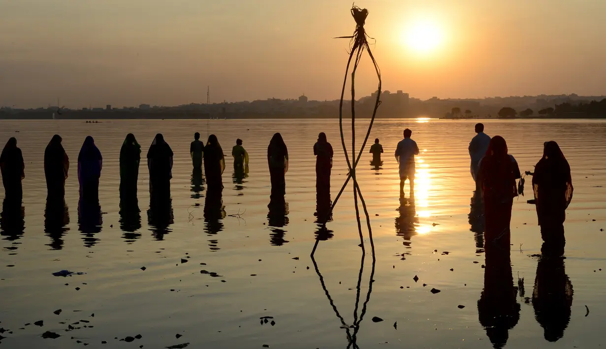 Umat Hindu India memanjatkan doa pada matahari pada festival Chhath di tepi Danau Hussain Sagar di Hyderabad, Selasa (17/11). Dalam festival tersebut, sejumlah umat Hindu berdoa saat matahari terbit dan tenggelam. (AFP PHOTO/NOAH Seelam)