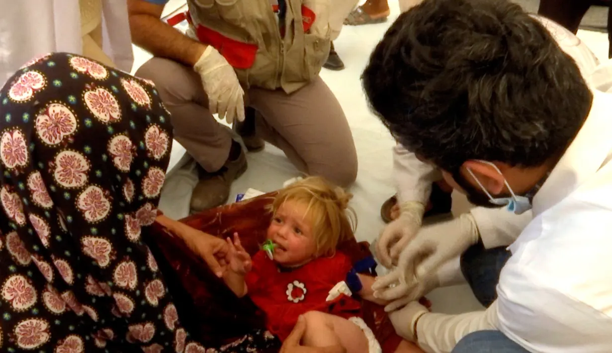 Seorang dokter memeriksa seorang gadis kecil yang dicurigai keracunan makanan di kamp Hassan Sham U2, Irak (13/6). Ratusan pengungsi keracunan makanan usai menyantap makanan buka puasa. (AP Photo/Balint Szlanko)