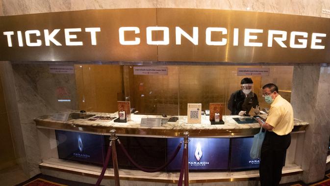 Pengunjung bioskop memakai masker untuk membantu mencegah penyebaran Covid-baru penyebab Covid-19 ketika ia membeli tiket di bioskop Paragon Cineplex di Bangkok, Thailand, Senin (1/6/2020). Kebijakan itu menyusul penurunan jumlah kasus penularan Covid-19. (AP Photo/Sakchai Lalit)