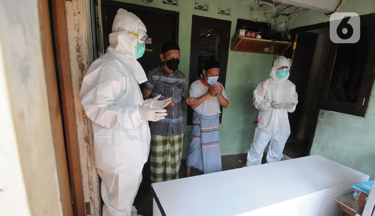 Tim relawan dari Polmas Bogor berdoa di depan peti jenazah warga korban COVID-19 yang meninggal saat isolasi mandiri di Bogor, Jawa Barat, Jumat (9/7/2021). Relawan menyediakan peti jenazah, memandikan, membungkus hingga membawanya ke tempat pemakaman khusus COVID-19. (merdeka.com/Arie Basuki)